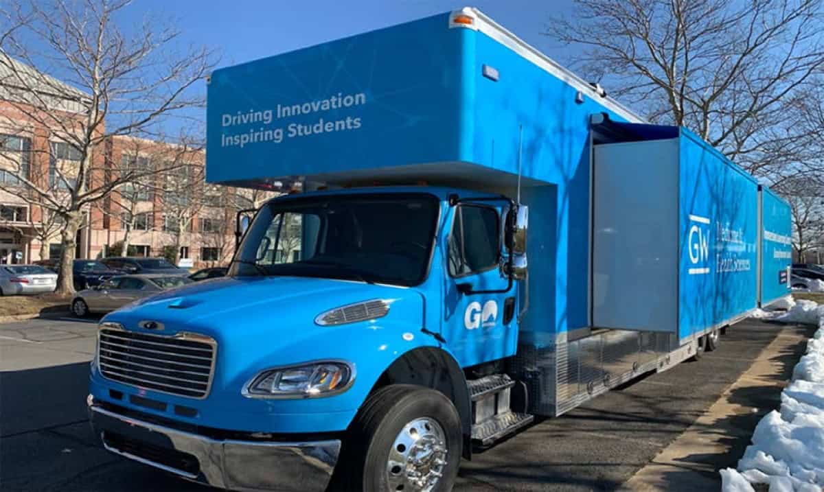 Vista esterna del George Washington University Truck, un grande camion blu con scritte promozionali.