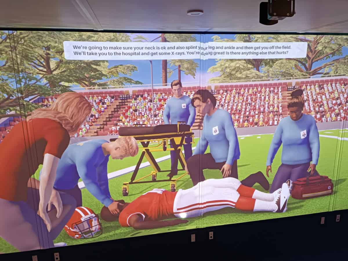 Simulazione di pronto soccorso su un campo di football americano con personaggi che assistono un giocatore infortunato.